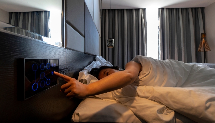 CI_Better-Business-Atmosphere_4.jpg Woman using bedside controls to open hotel blinds