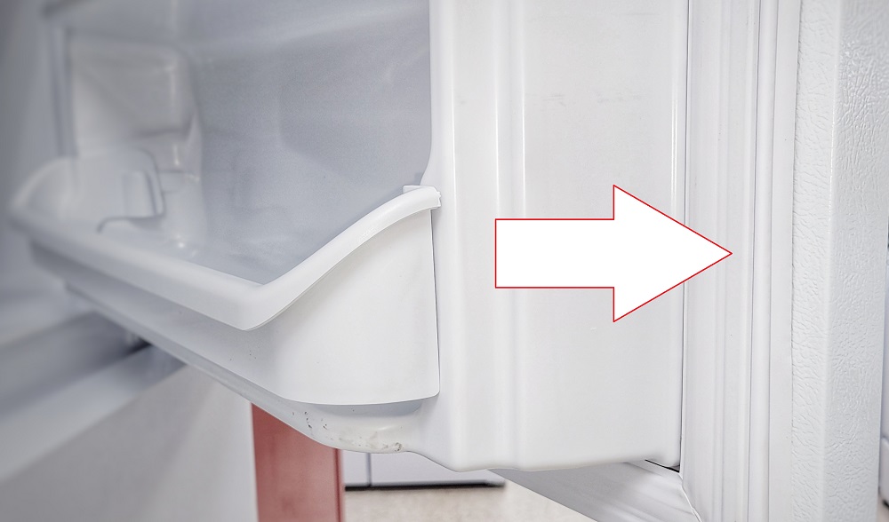 Graphic arrow pointing to inside refrigerator gasket