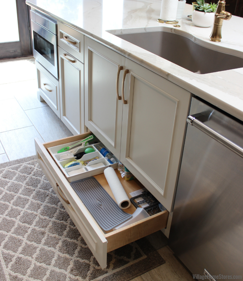 Kitchen sink base with bottom drawer layout. Drawer shown open with cleaning supplies. 