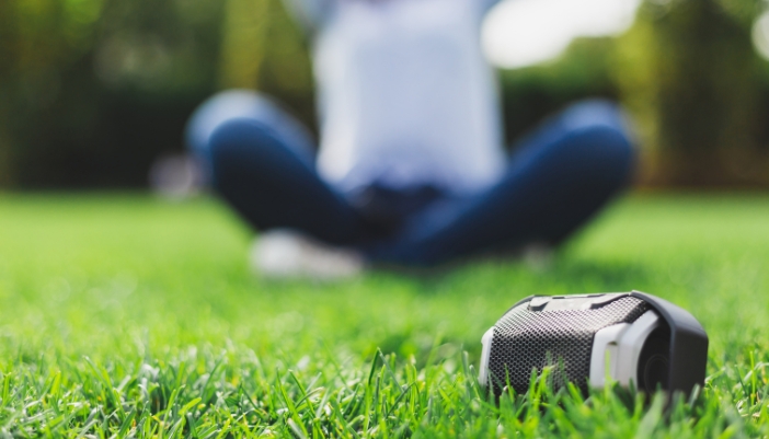 Elec_Springtime-Outdoor-Tech_1.jpg Closeup of someone listening to portable speaker in the park