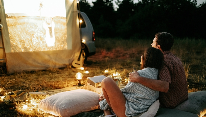 Elec_Springtime-Outdoor-Tech_3.jpg A couple watching a movie on a portable projector while camping
