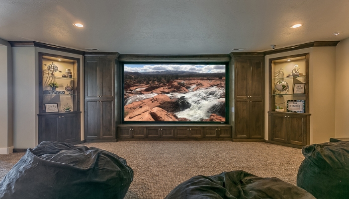 A home theater room with a large TV, surround sound, and bean bag chairs for seating.