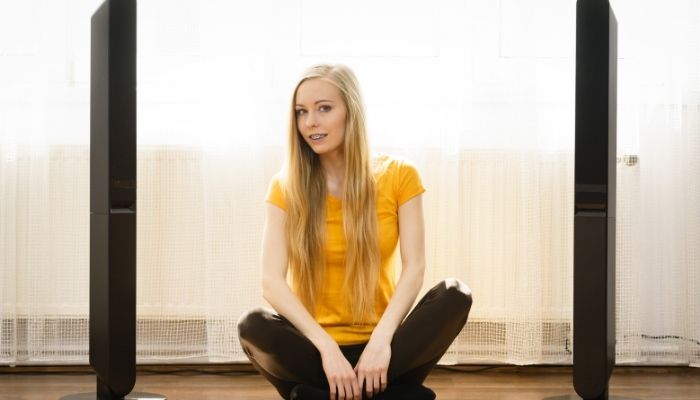 woman sitting between two soundbars