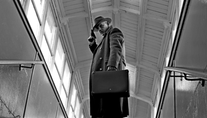 A noir-era style film with a detective looking around with a gun