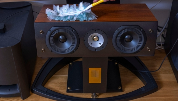person dusting speakers