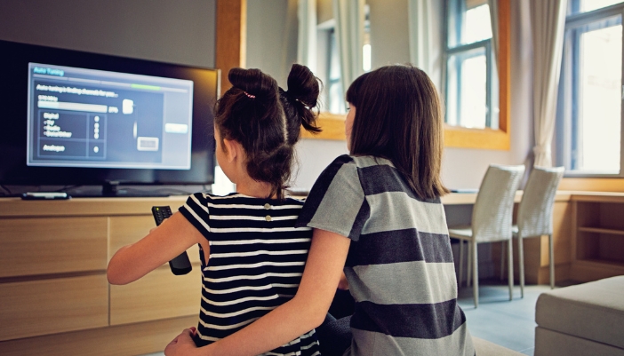 A closeup of a mother and child adjusting the TV settings