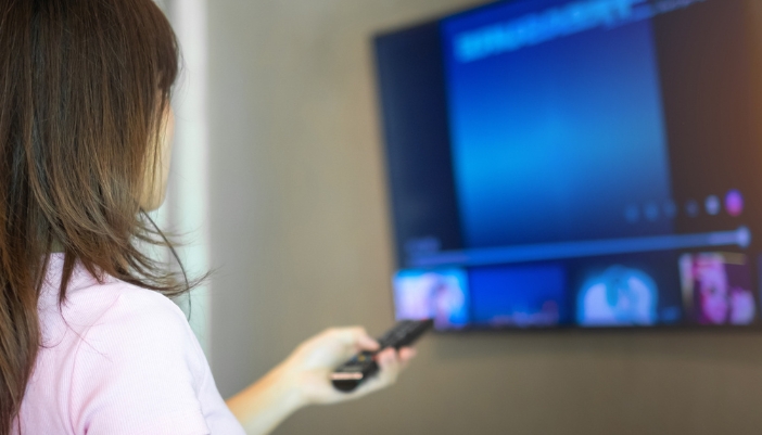 Closeup of a woman adjusting the settings on her TV