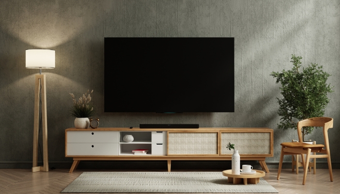 A mounted flat screen TV on a gray wall above a white and wood console table.