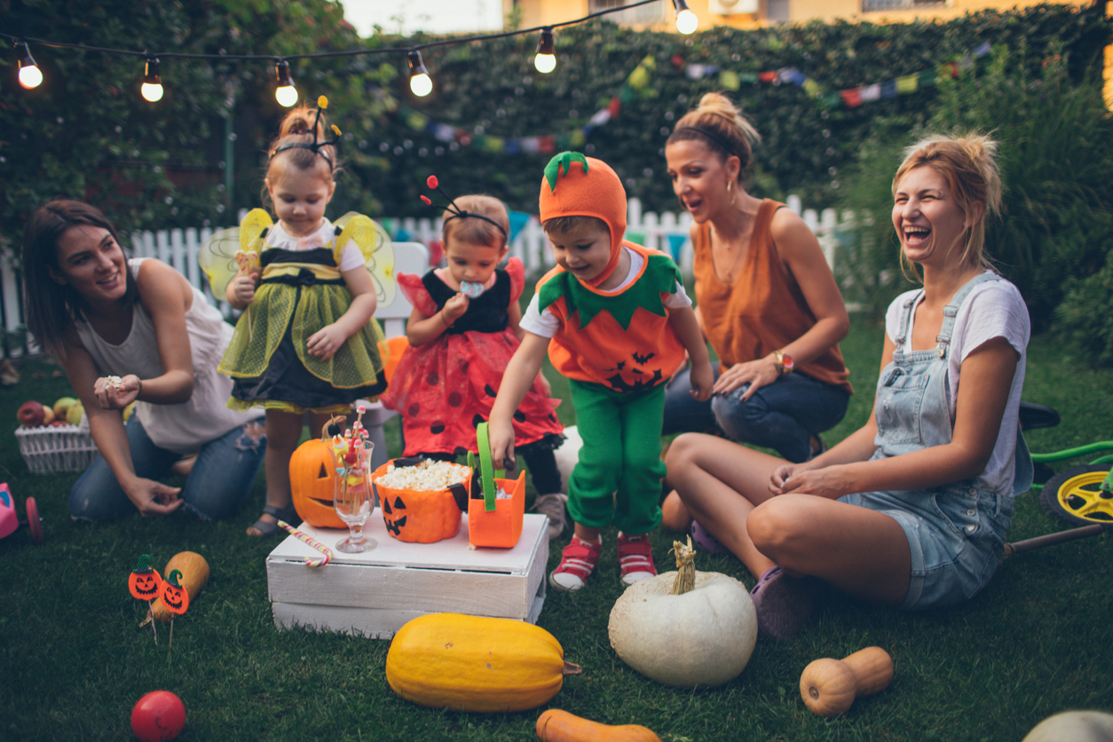 iStock Credit: AleksandarNakic mothers with children in Halloween costumers watch movie outside with popcorn