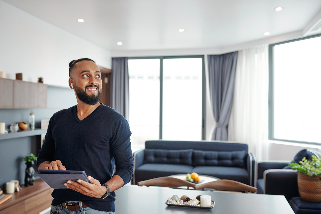 excited man using smart home application on digital tablet to open curtains and turn off lights
