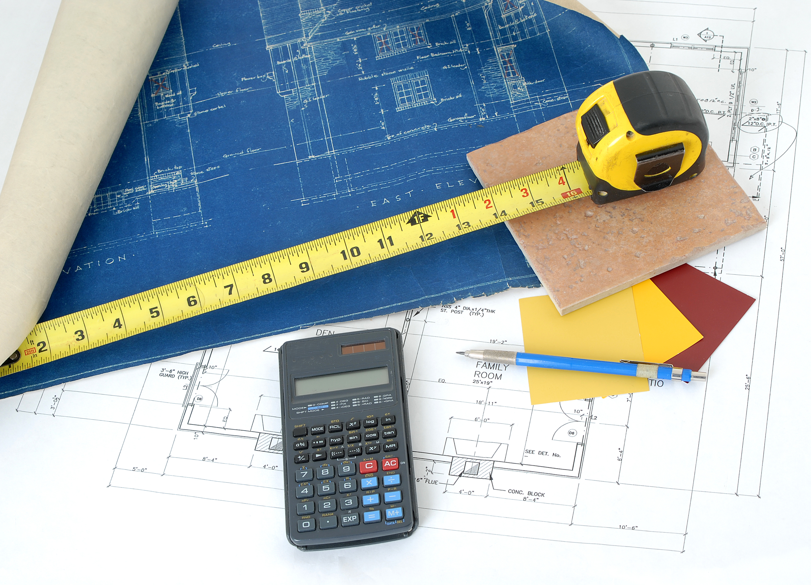 An overhead view of a blueprint, tape measure, flooring samples, and calculator