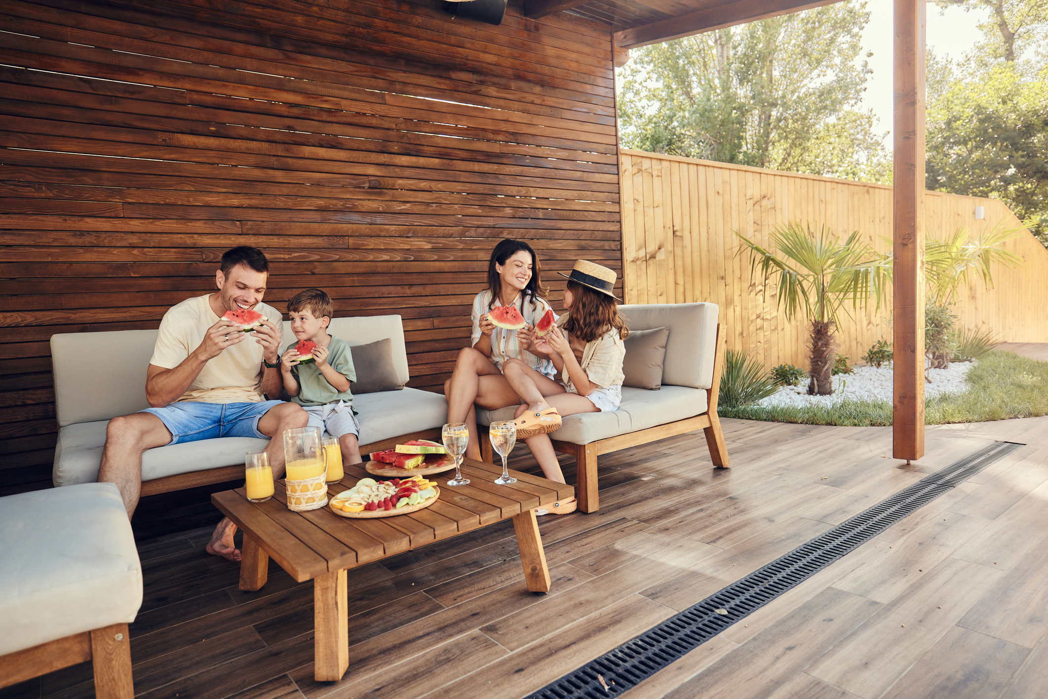 A family of four enjoying a meal on outdoor furniture.