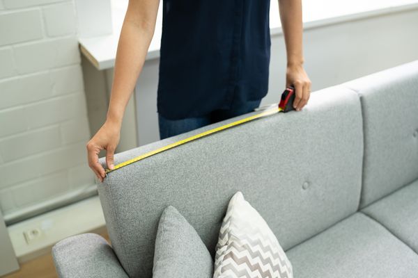 iStock Credit: AndreyPopov A person measuring the back of a sofa