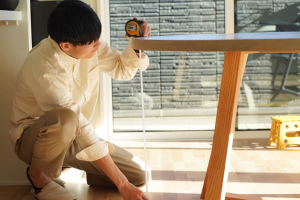 iStock Credit: yamasan A man measuring the height of a dining table