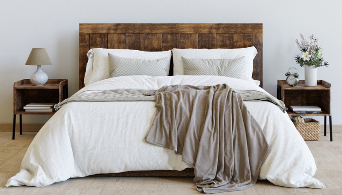 A modern bed with a dark wood panel headboard.