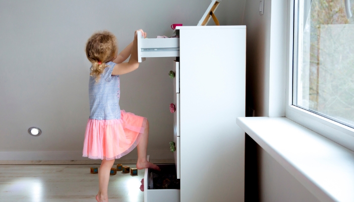 Furn_Childproofing-Furniture_1.jpg A child using drawers to climb up a drawer chest