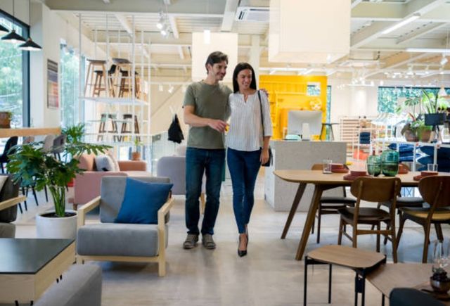 Front view of a couple walking through a furniture store and smiling