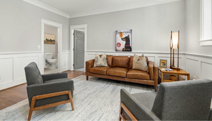 A modern living room with a dog poster and a brown leather couch.
