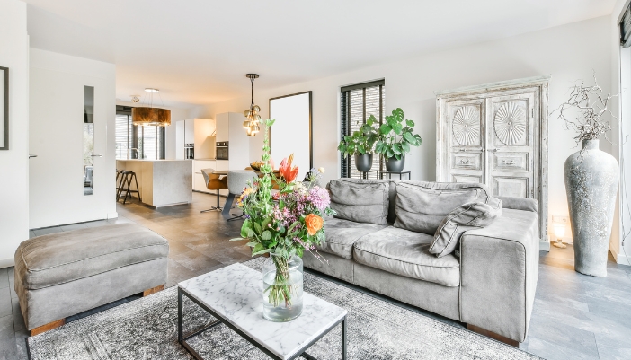 A modern living room with gray fabric furniture and floral arrangements.