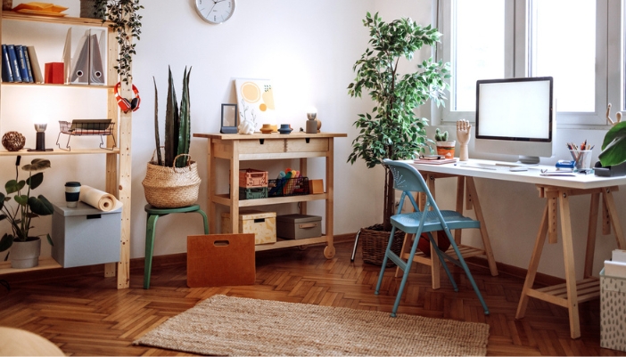 A well-lit home office with several plants and natural wood accents.