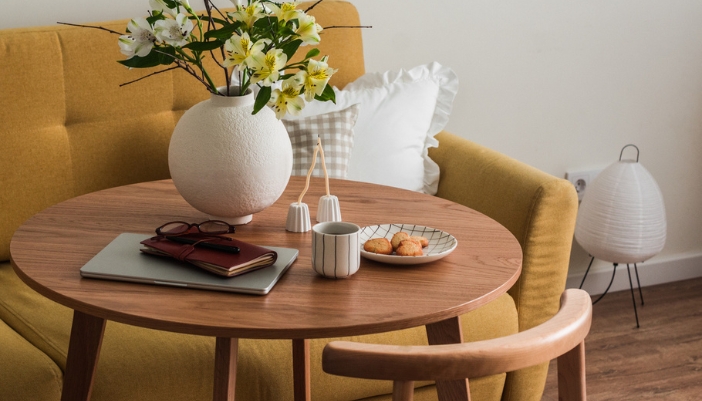 Close-up of a round wooden dining table with a couch for seating and a rounded chair.