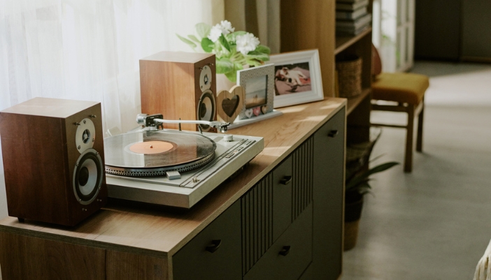 A record player on a media console with closed shelving.