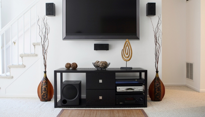 A close-up of a modern media console with a DVD player and speakers. 