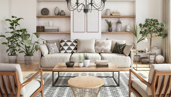 A gray couch with several geometric pillwos on it sits in front of a pair of bookshelves.