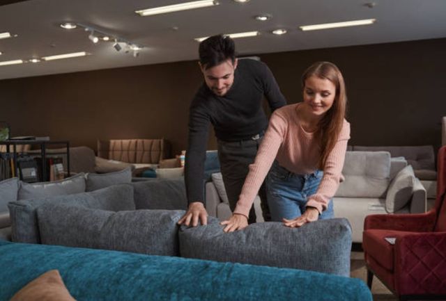 Front view of a couple feeling a sofa in a furniture store