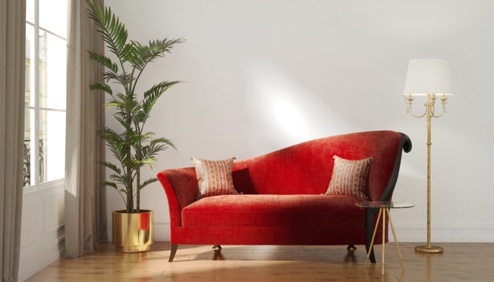 A velvet red daybed sits in a modern living room with a neutral wall.