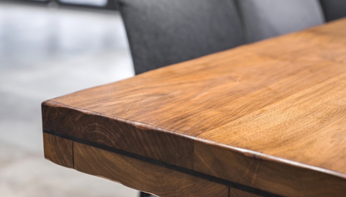 Close-up of the corner of a solid wood tabletop showing its grain and warm finish