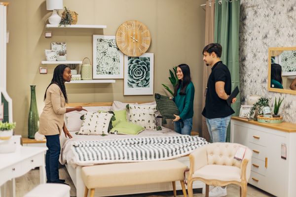 iStock Credit: Kosamtu A couple inspecting a bedroom set with a salesperson