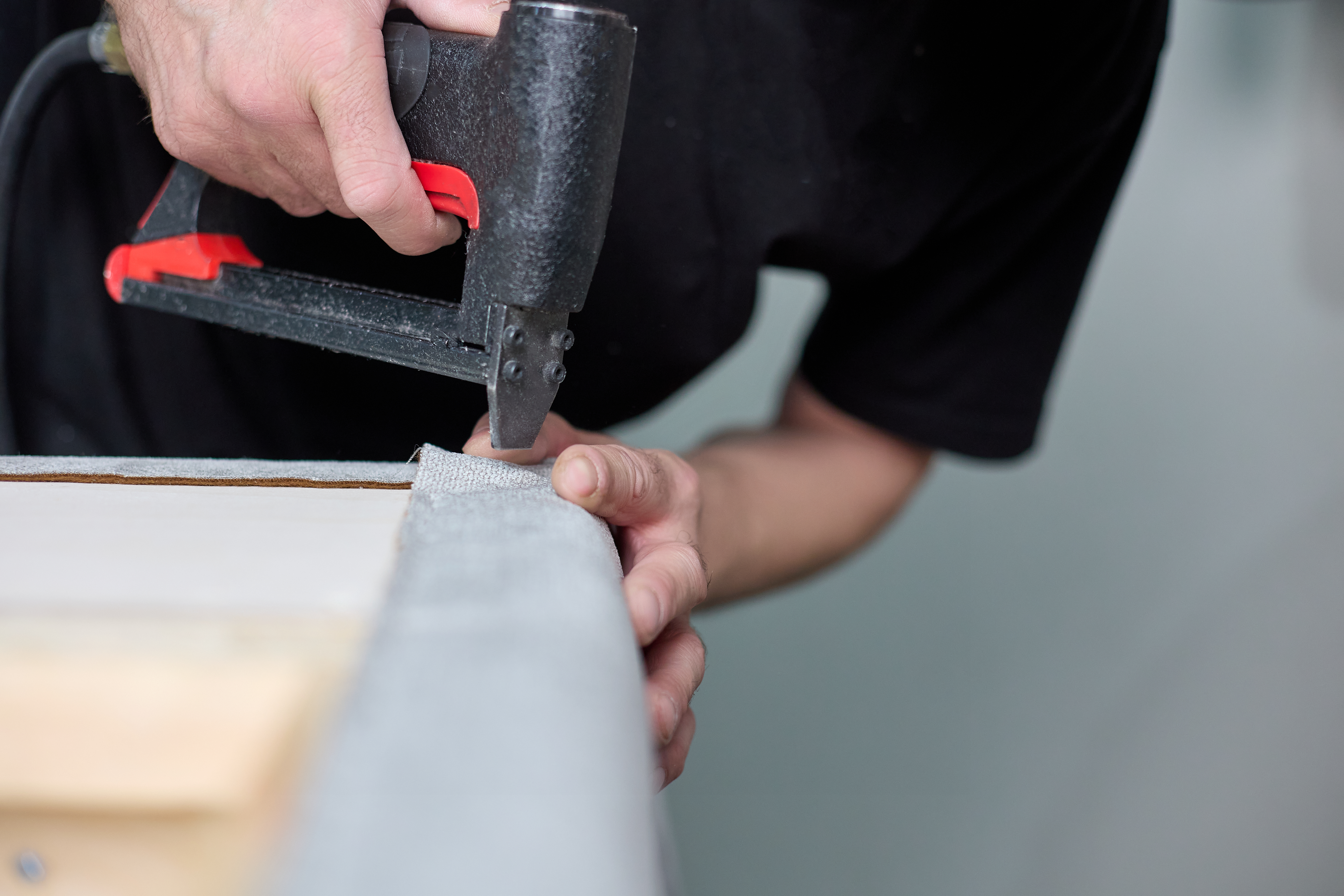 A person stapling down fabric on a sofa 