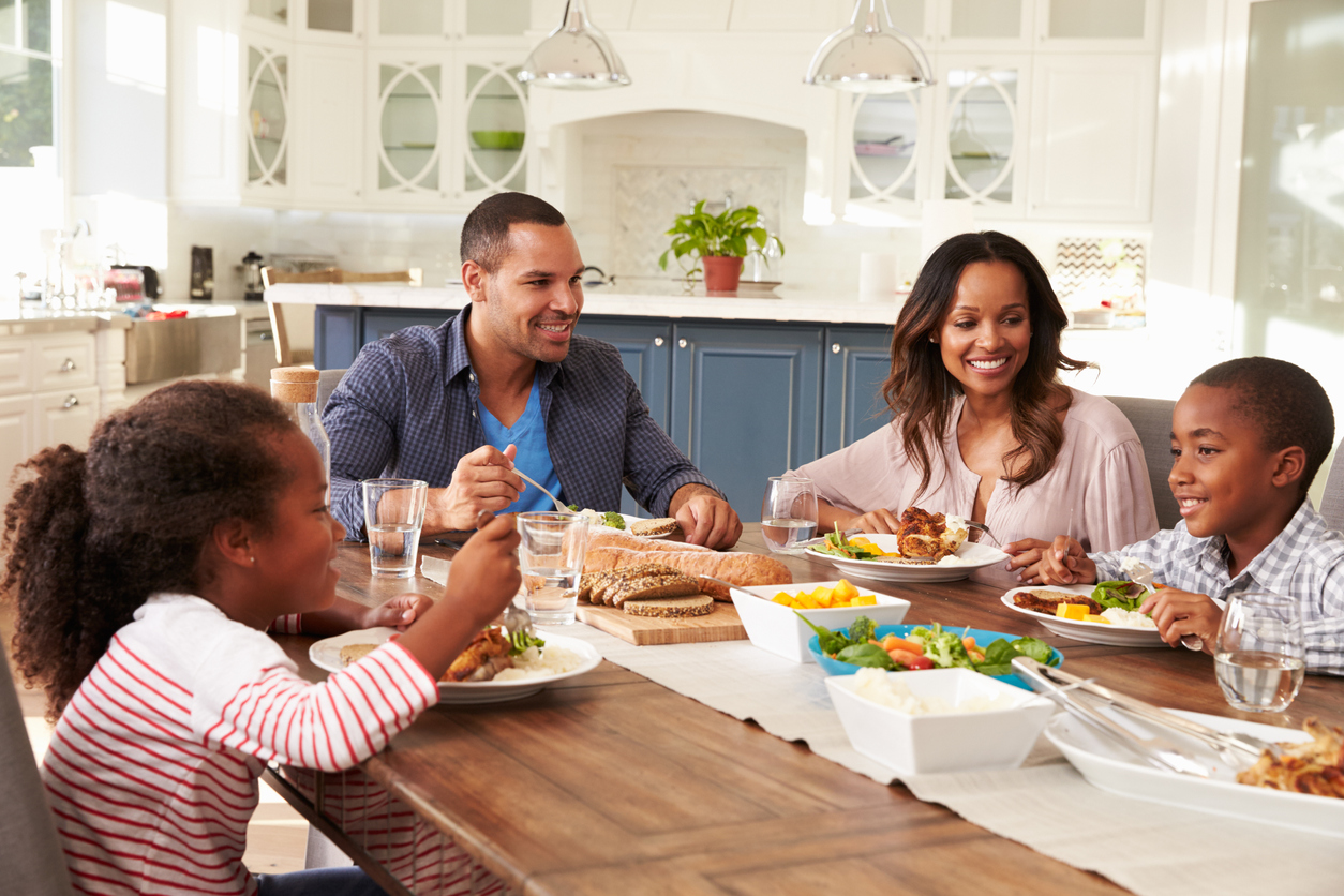 Young family gathered around a dining table and eating