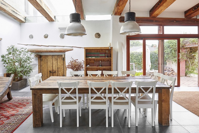 A dining room space featuring a farmhouse table and white chairs