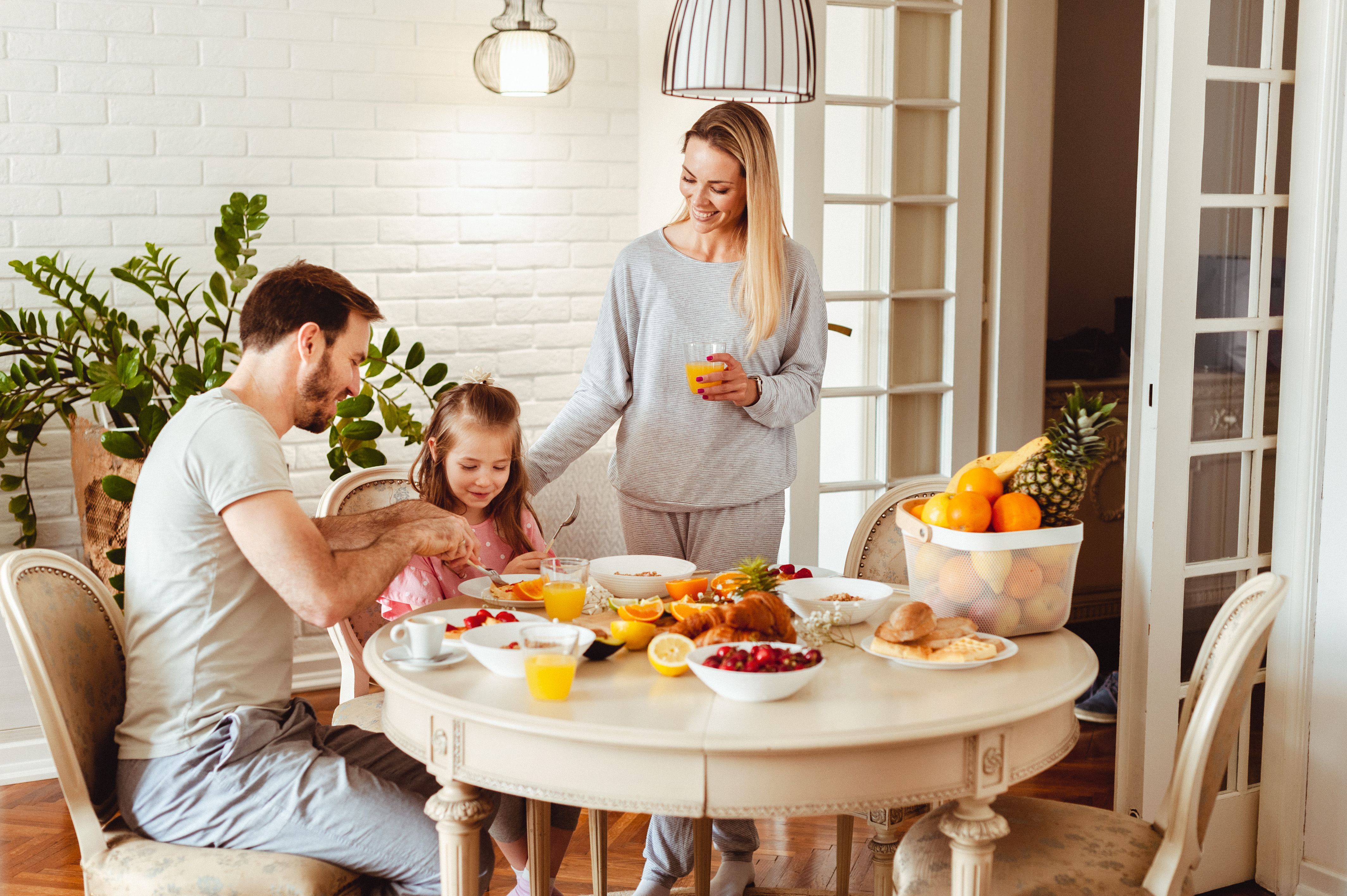 A mother, father, and daughter gathered around a round table iStock Credit: Zukovic A mother, father, and daughter gathered around a round table