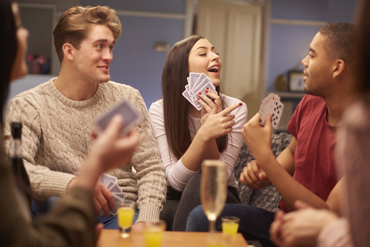 iStock Credit: sturti young friends sit on the sofa and play a game of cards at party