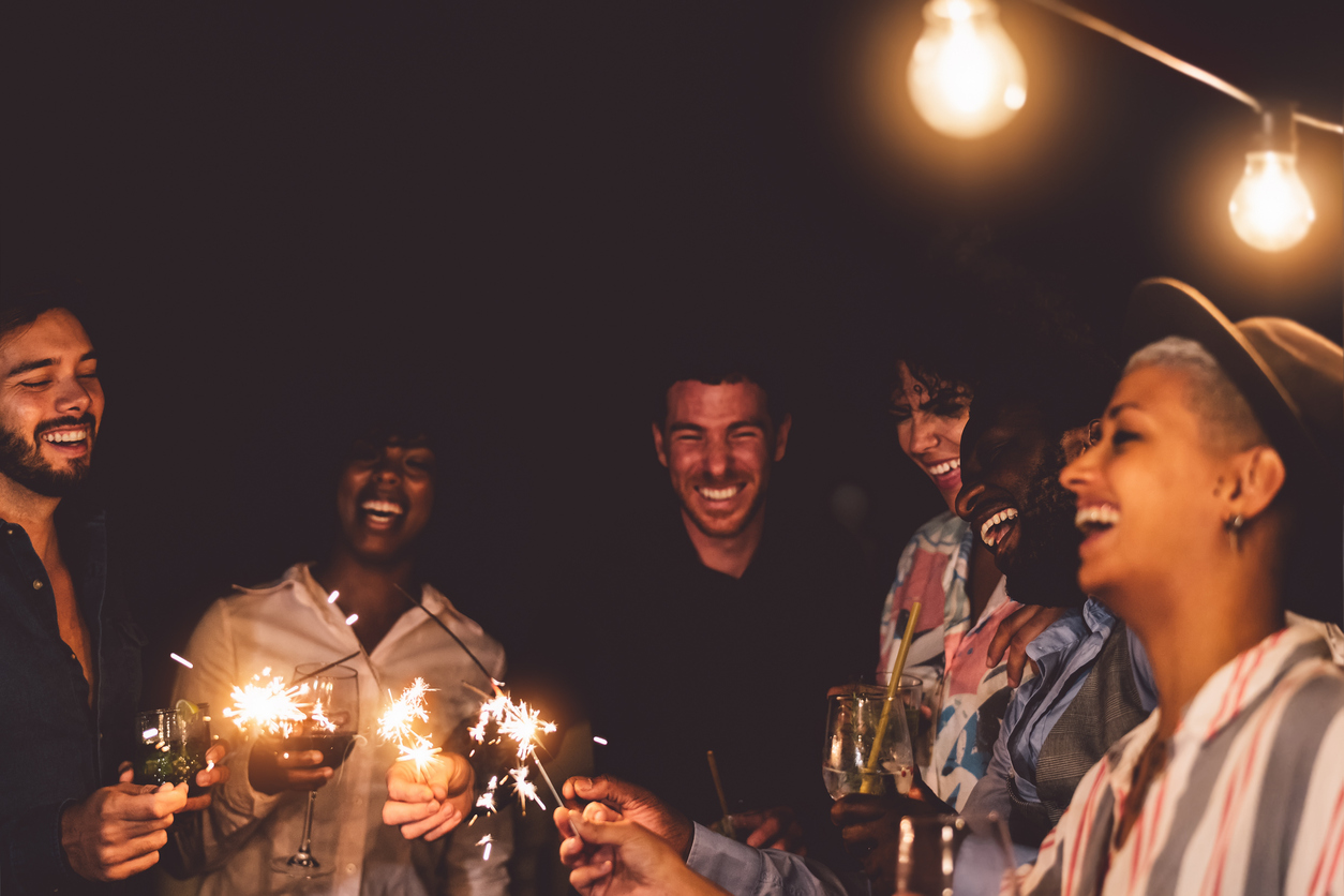 iStock Credit: Alessandro Biascioli young friends celebrating new year eve with sparklers on patio