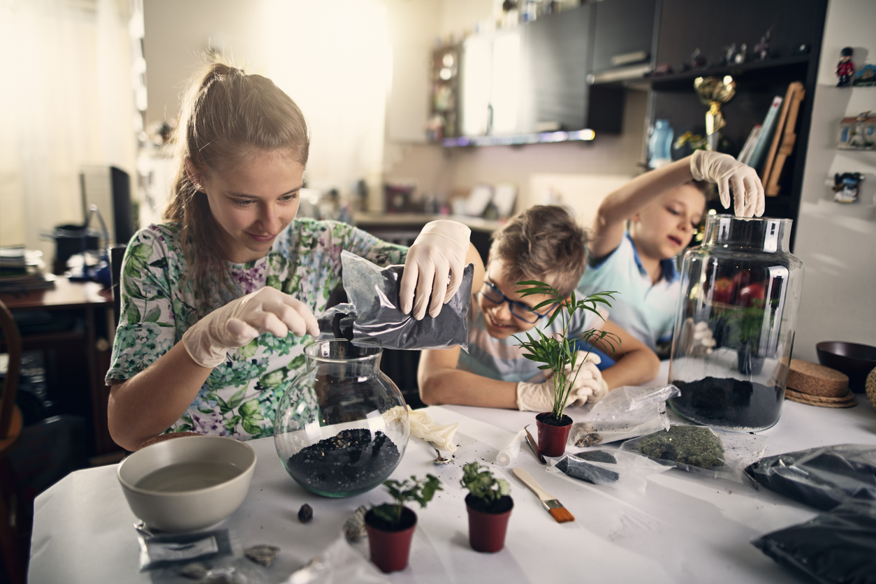 iStock Credit: Imgorthand three children creating terrariums with a variety of plants