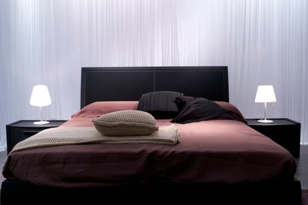 iStock Credit: image_of_life A black bed frame with bedding and lighting