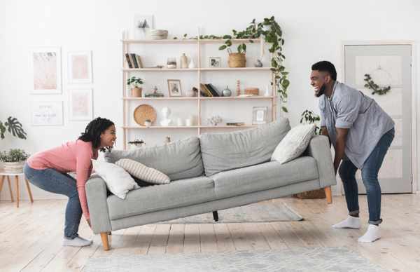 A smiling man and woman lifting a sofa