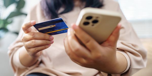A close-up of a woman holding a credit card and smartphone 