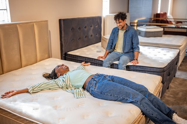 Front view of a man and woman happily shopping for a new mattress in a mattress store