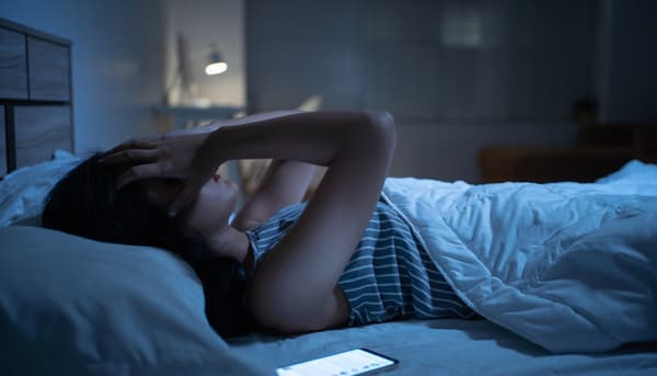 A woman in bed grabbing her head