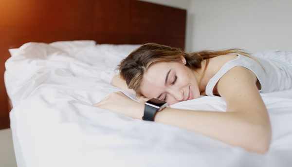 A smiling woman lying stomach-down on a mattress