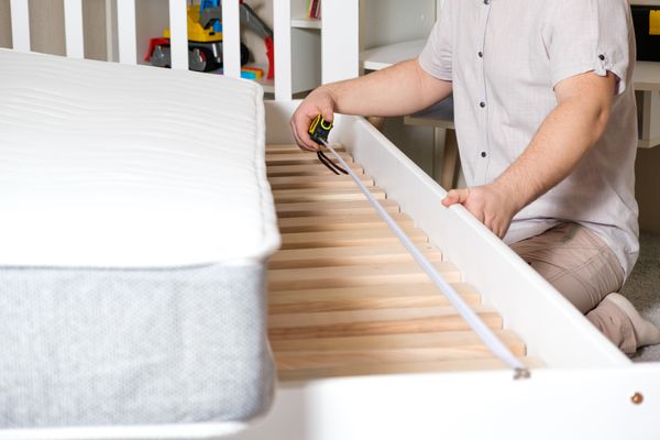 A person measuring a bed frame
