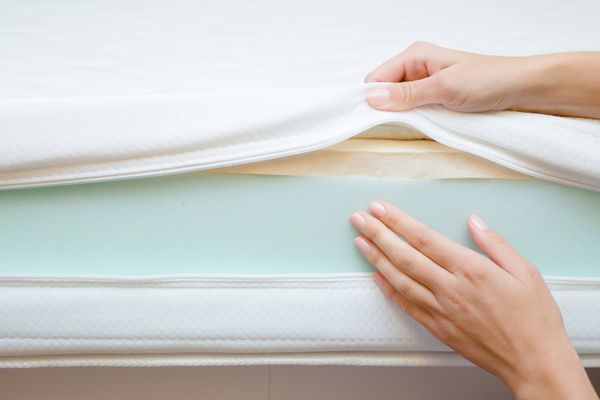 A person revealing the layers of a memory foam mattress