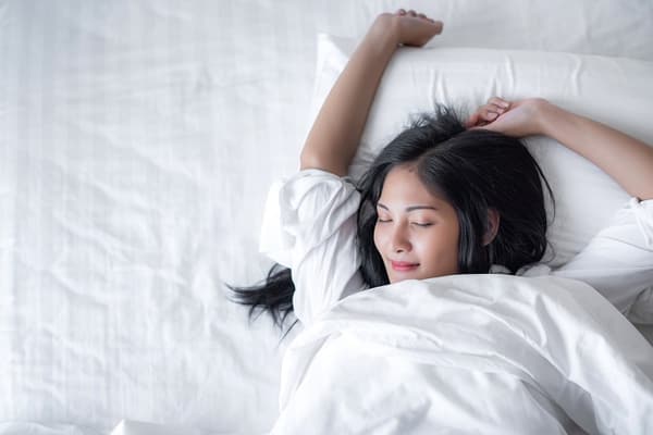 Overhead view of a woman stretching in bed