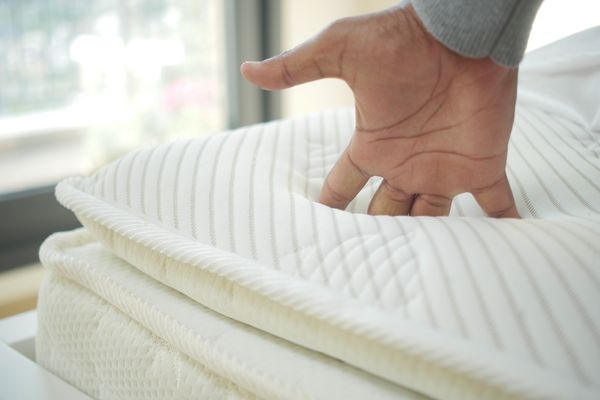 A person pushing into a mattress