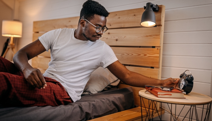 Man setting alarm clock as he gets ready for bed